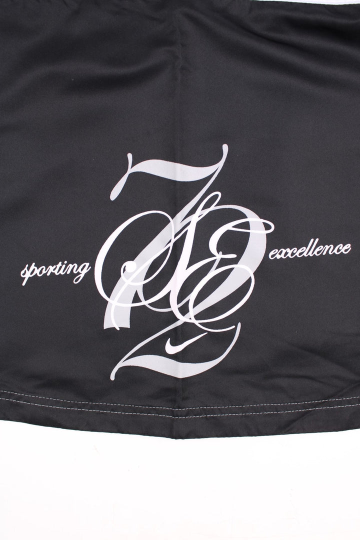 Y2K Nike Sporting Excellence Mini Skirt in black and white colourway with the logo and graphic spell out printed around the left side.