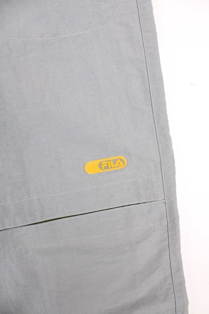 Y2K Fila Cargo Trousers in a grey colourway with big pockets on the front and zip at the bottom for detachable quarter length shorts option, and has the logo embroidered on the front left leg.