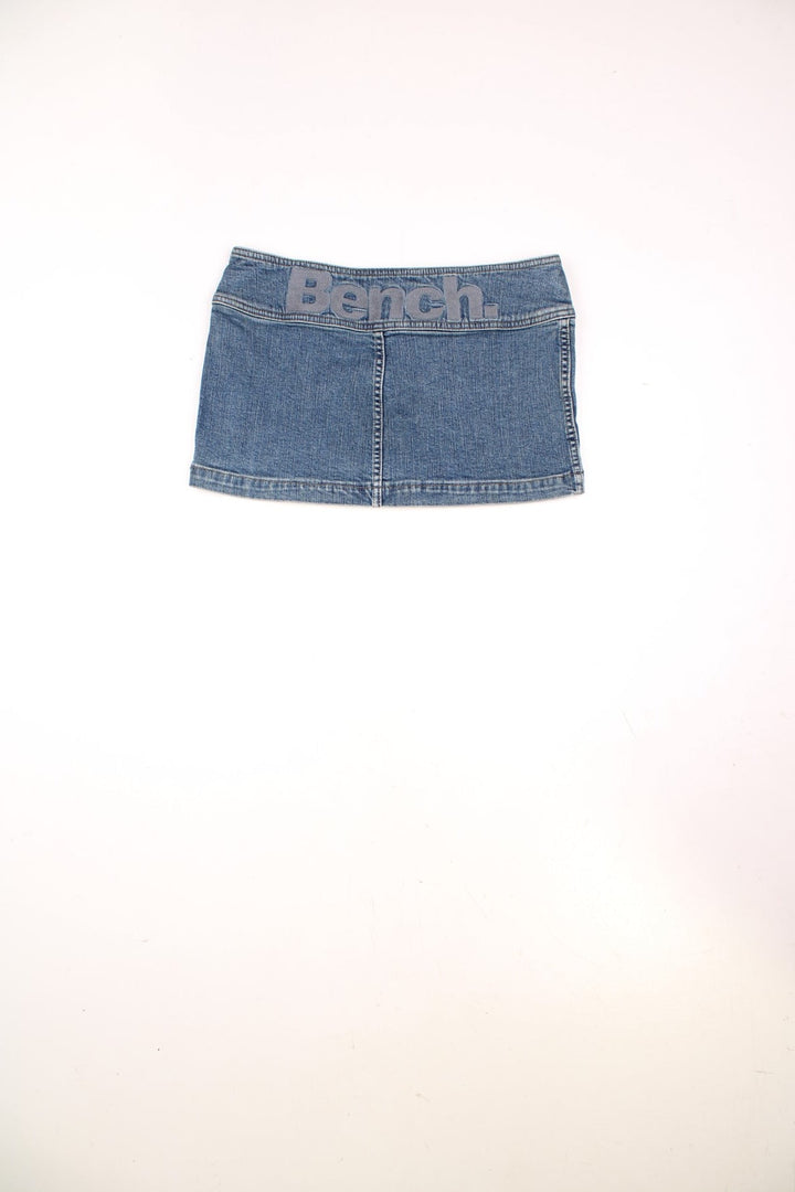 Y2K Bench denim mini skirt with belt buckle detailing, zip closure, and a spellout on the back. 