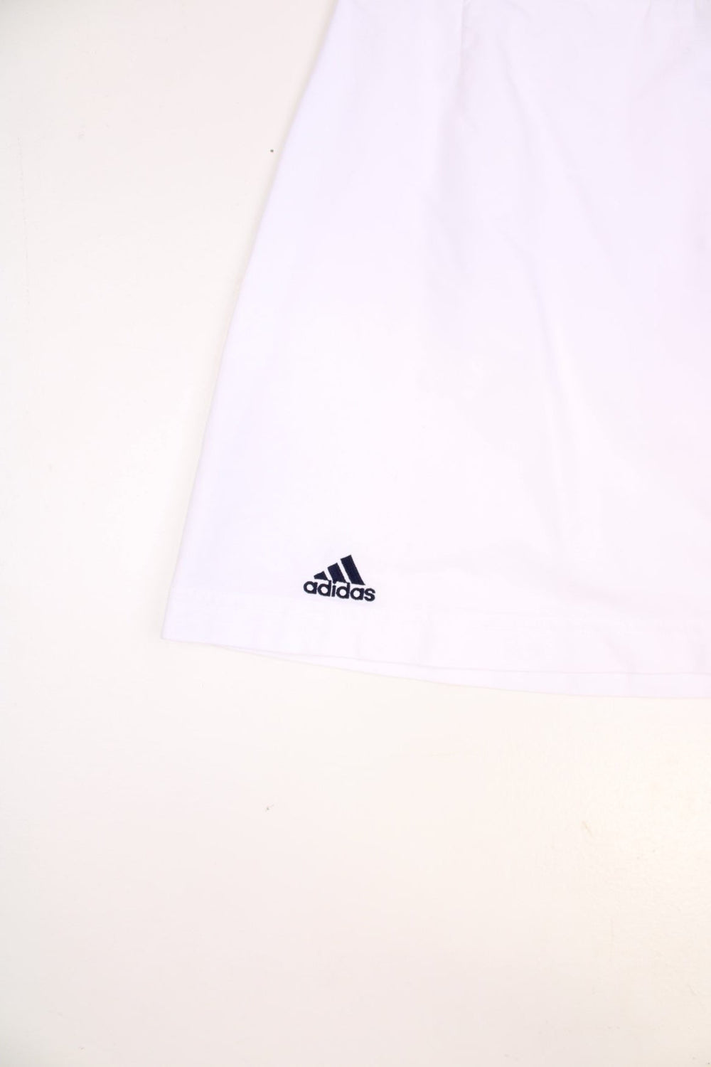 Y2K Adidas mini tennis skirt in white with blue three-stripe design on one side. 