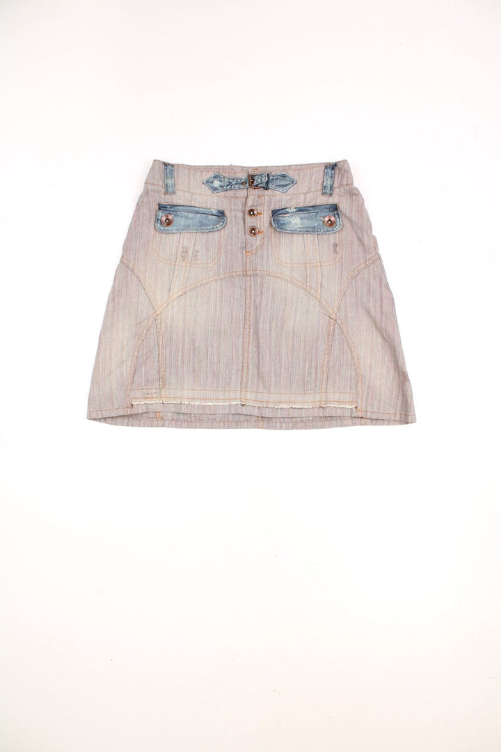 Y2K tan herringbone denim mini skirt by Chipie with blue denim accents, button closure, buckle detailing, front and back pockets, and a pink embroidered logo patch on the back. 