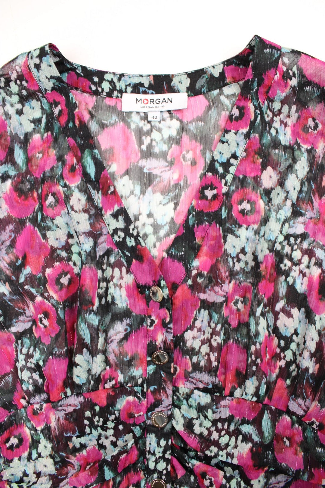 Morgan de Toi blouse in black with a hot pink and blue floral pattern, button closure and shirred hem at the back.