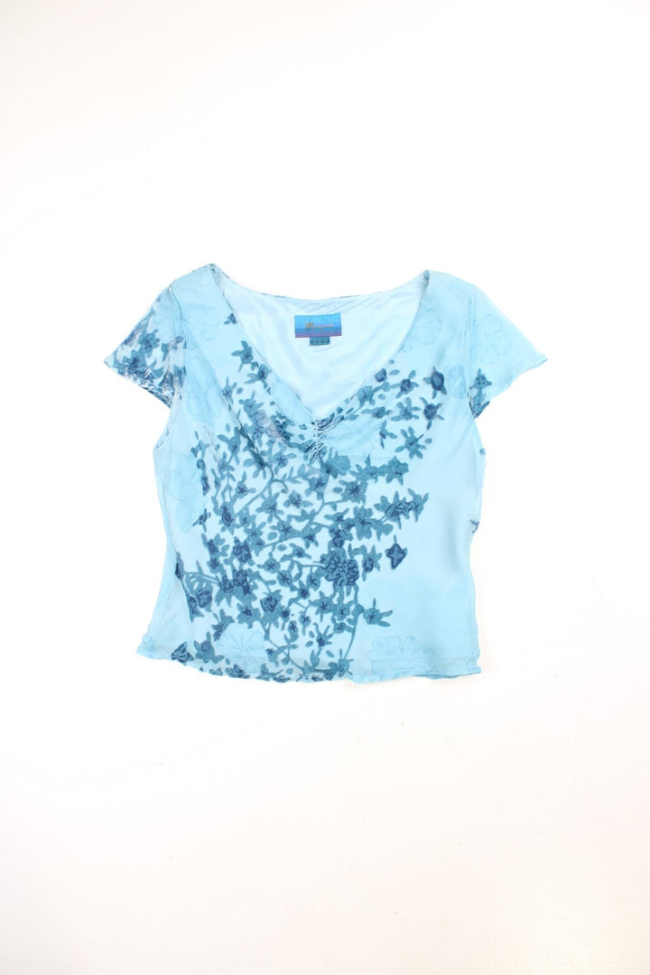 Y2K Monsoon floaty top in blue with cap sleeves, a ruched bust, and velvet floral appliqué.