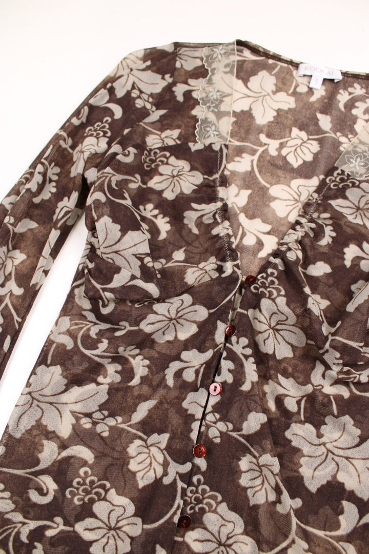 Y2K Kookai mesh top in brown with a white floral print, button closure, and a white lace trim around the neckline.