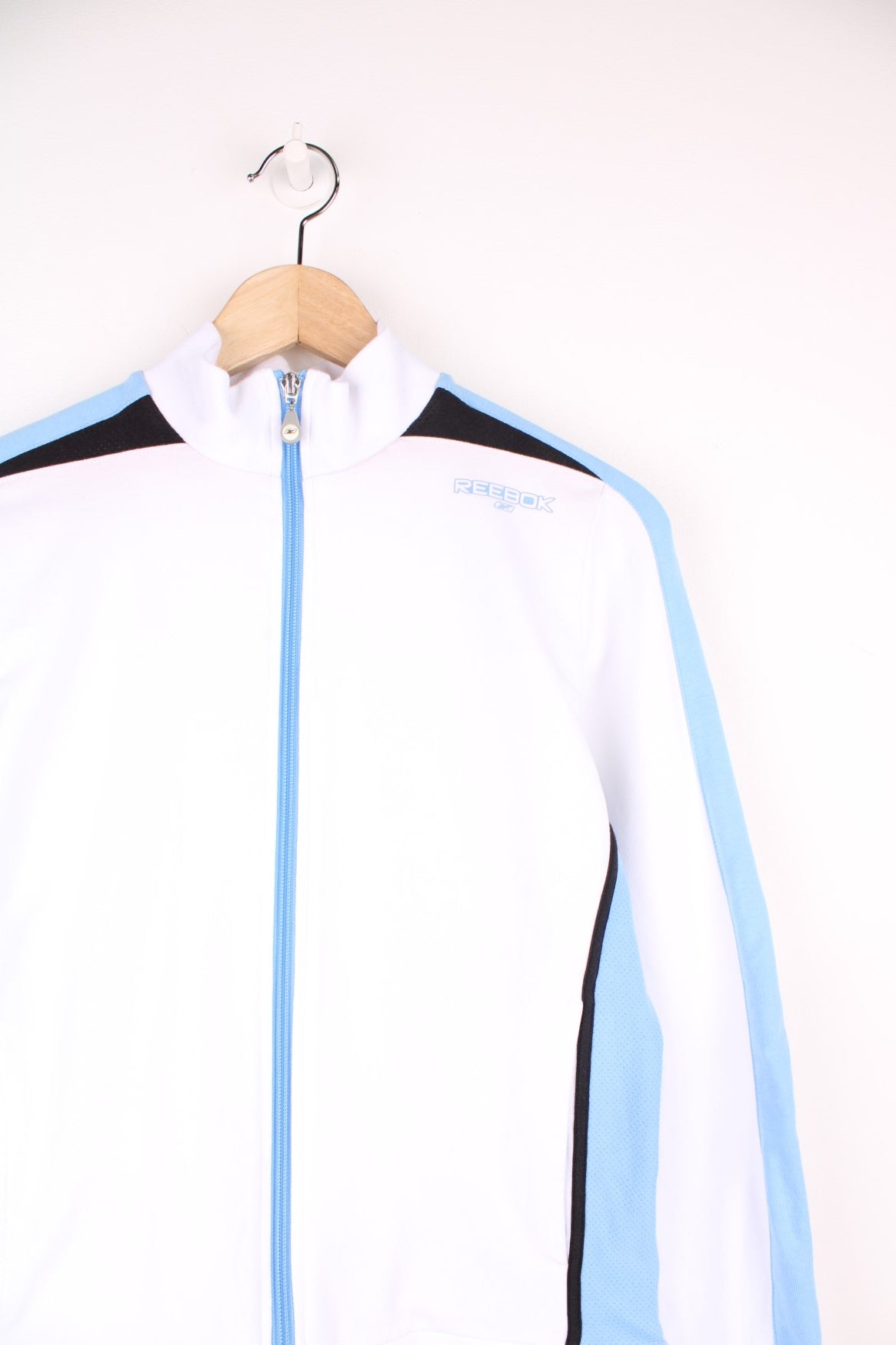 White Reebok zip through sweatshirt with blue stripe down each sleeve and puff printed logo.