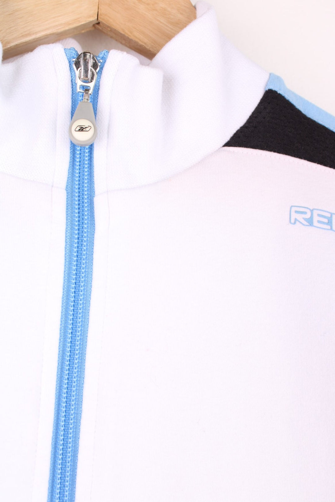 White Reebok zip through sweatshirt with blue stripe down each sleeve and puff printed logo.