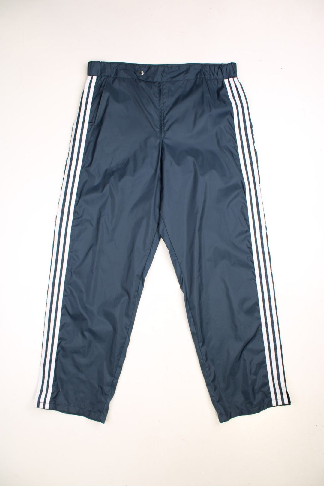 Vintage Adidas Tracksuit Bottoms in navy blue colourway with the iconic three stripes going down the legs, has pockets and the logo embroidered on the back.