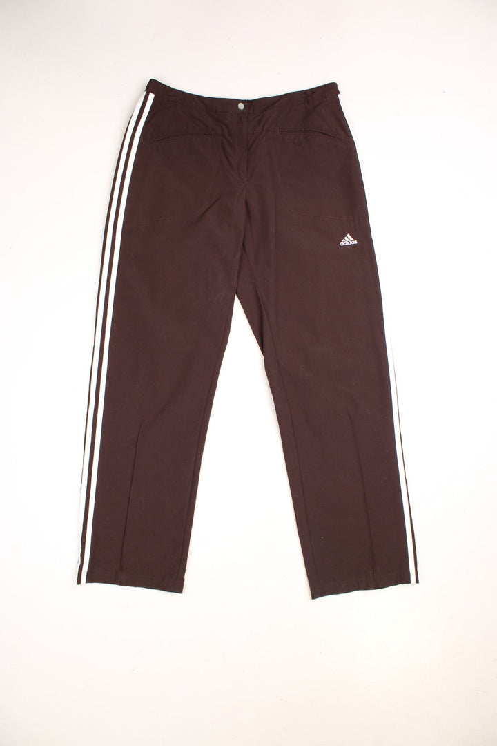 Adidas Trousers in brown and white colourway with the three iconic stripes going down the legs, mid rise and has multiple pockets and the logo embroidered on the front.