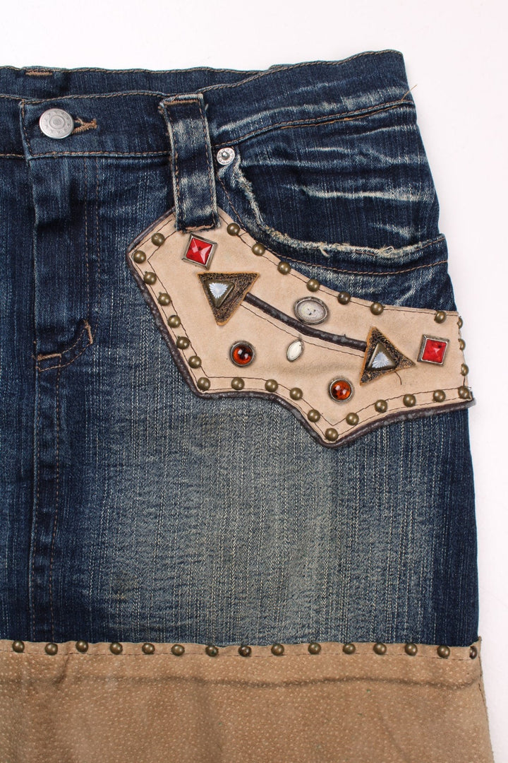 Y2K embellished denim mini skirt in blue with faux suede patches, zip and button closure, and four pockets by AMN&SIA Paris.