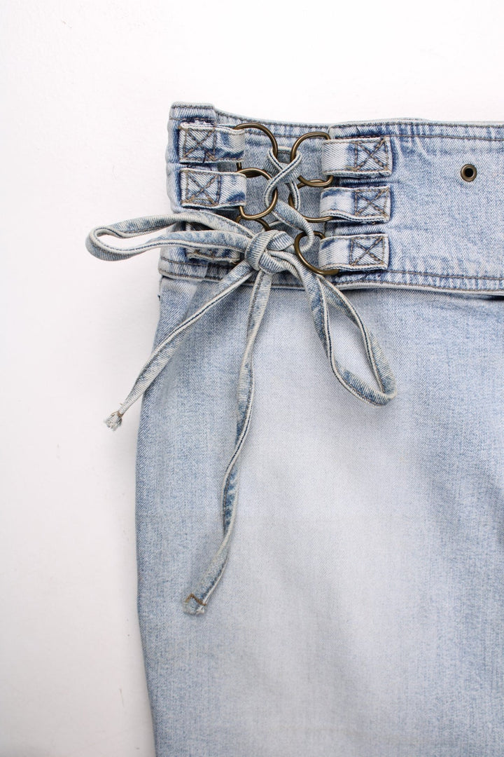 Y2K Armani Jeans denim mini skirt in a light blue wash with concealed zip and button closure, an attaced lace-up belt, and eyelet detailing around the waist .