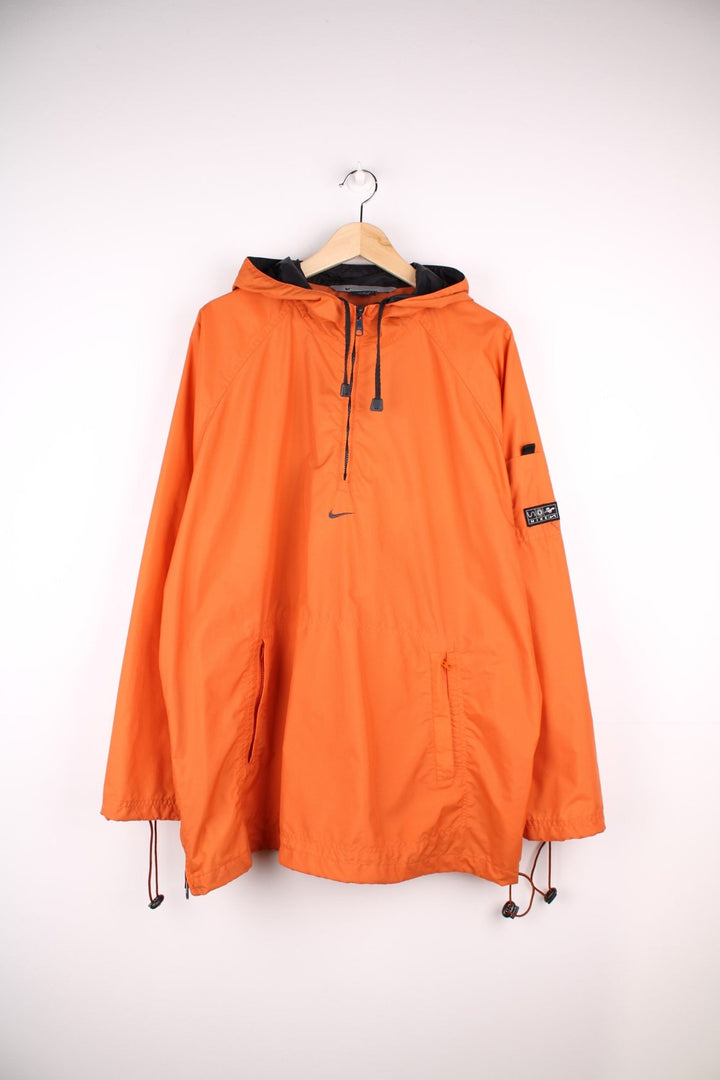 Nike Pullover Windbreaker in a orange colourway. Zips up half way and has a big pouch pocket, hooded, and has the swoosh logo embroidered in the centre.