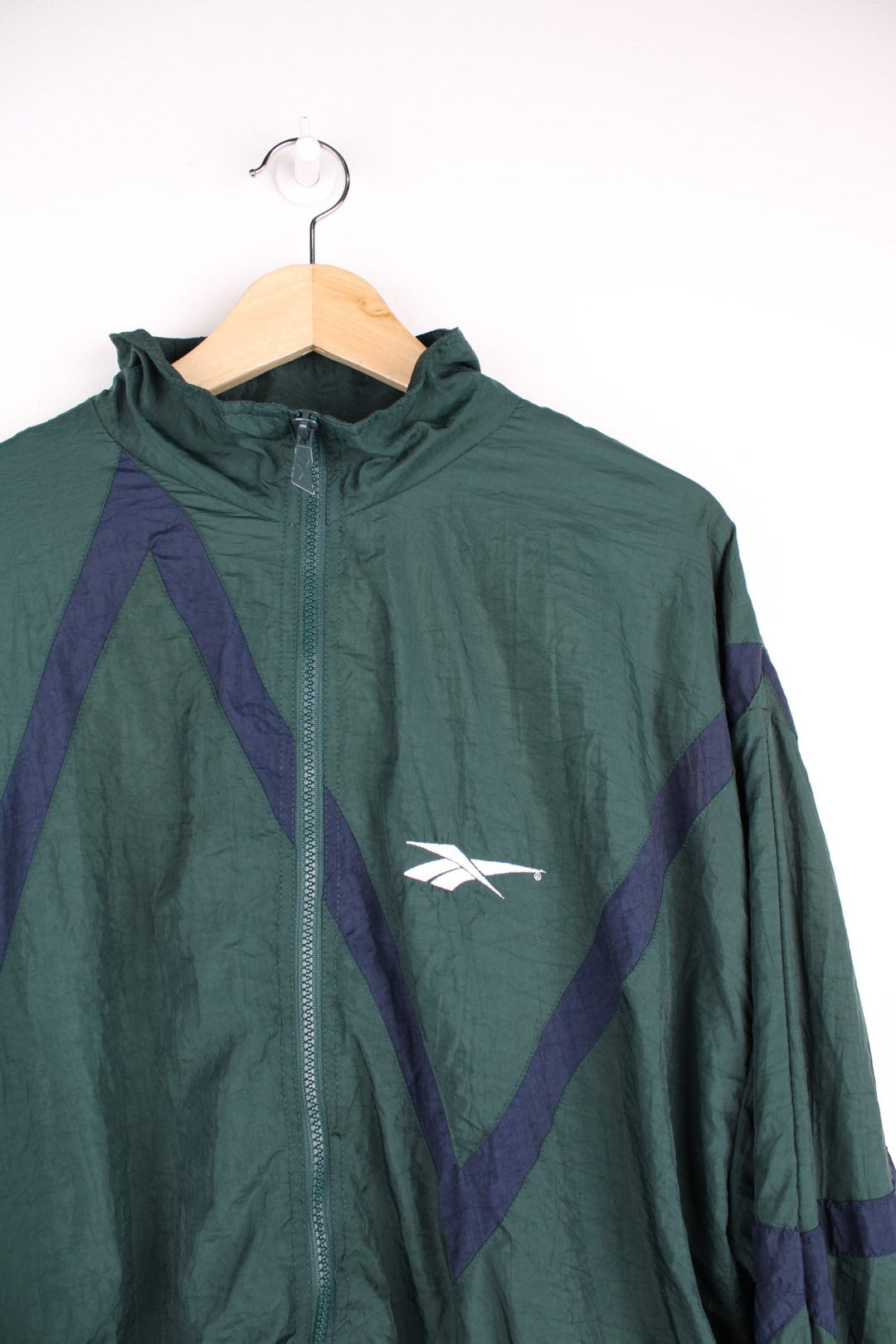  Tracksuit Jacket in a  colourway with navy blue patterned stripe going across the front and back. Zips up and has side pockets, and the logo is embroidered on the front.