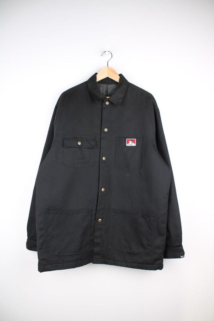 Ben Davis Chore Jacket in a black colourway. Buttons up and has multiple pockets, insulated with a blanket lining, and has the logos embroidered on the front.