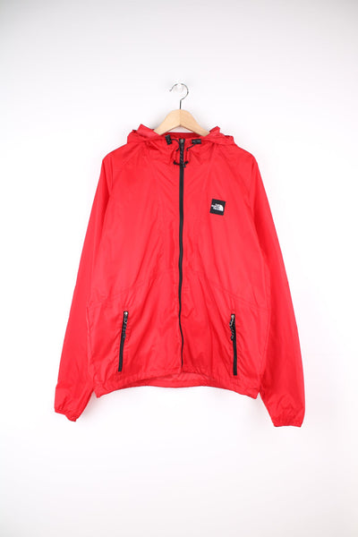 The North Face windbreaker rain jacket in red. Features embroidered logo on the chest.