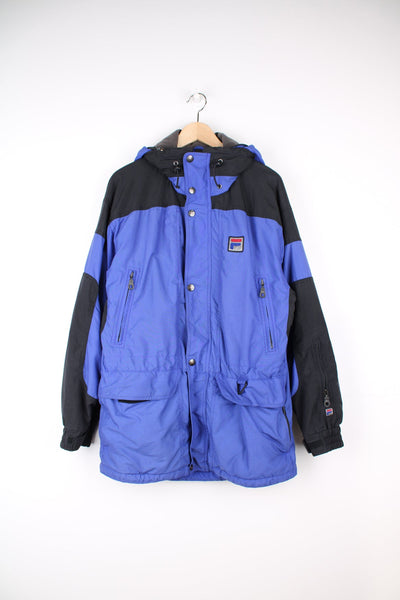 Vintage Fila "Alpine" coat. Features multiple pockets, embroidered logo on the chest and fold away hood.