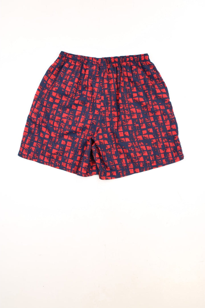 Nike Patterened Shorts in a red and navy blue colourway, has an elasticated waist with drawstring, side pockets, and the swoosh logo embroidered on the front. 