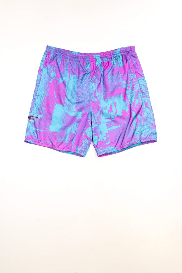 Vintage Nike Flight Shorts in a purple and blue patterned colourway, has an elasticated waist with drawstrings, side pockets, and the logos embroidered on the front. 