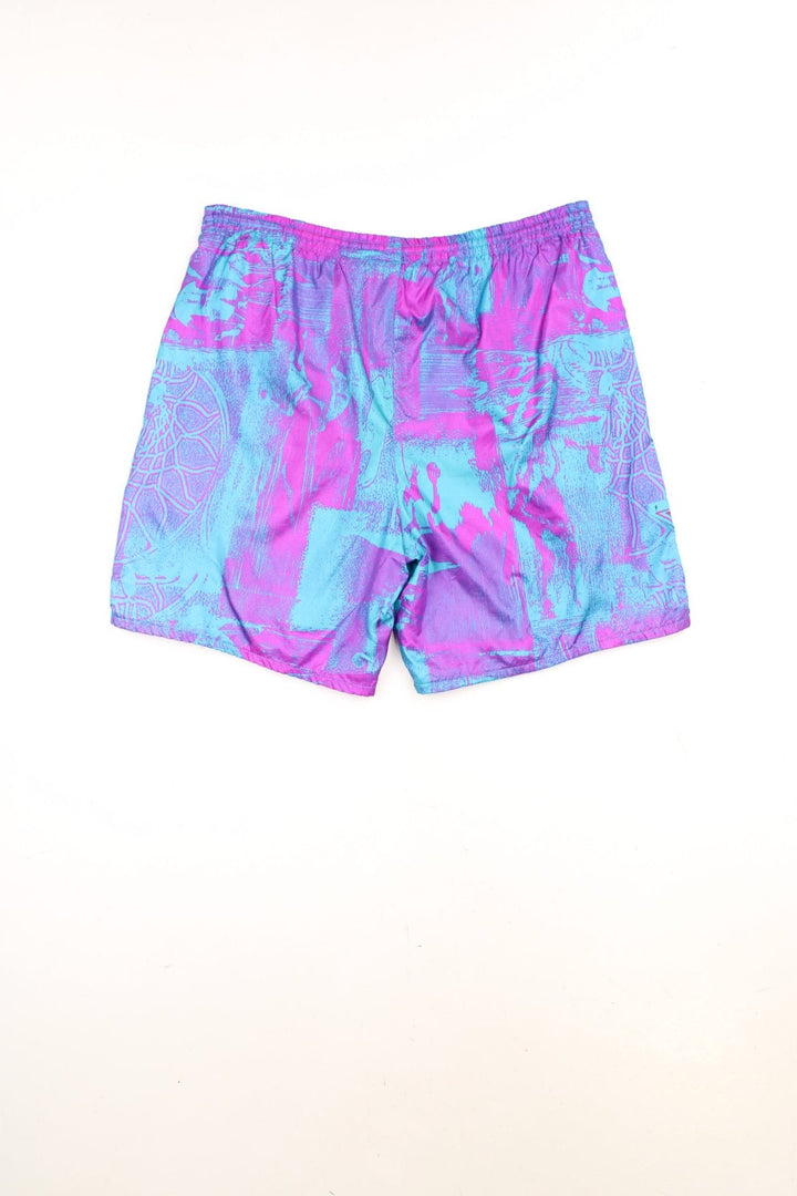 Vintage Nike Flight Shorts in a purple and blue patterned colourway, has an elasticated waist with drawstrings, side pockets, and the logos embroidered on the front. 