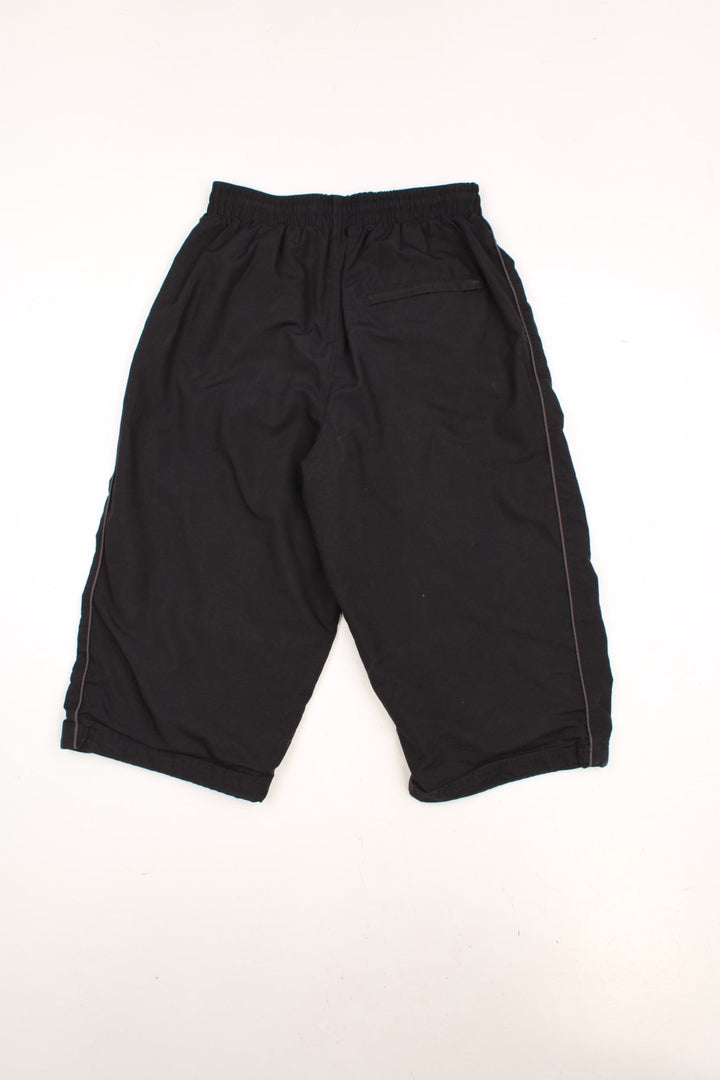 Umbro 3/4 Length Shorts in a black colourway, has an elasticated waist with drawstrings, side pockets, and the logo embroidered on the front and going down the left side. 