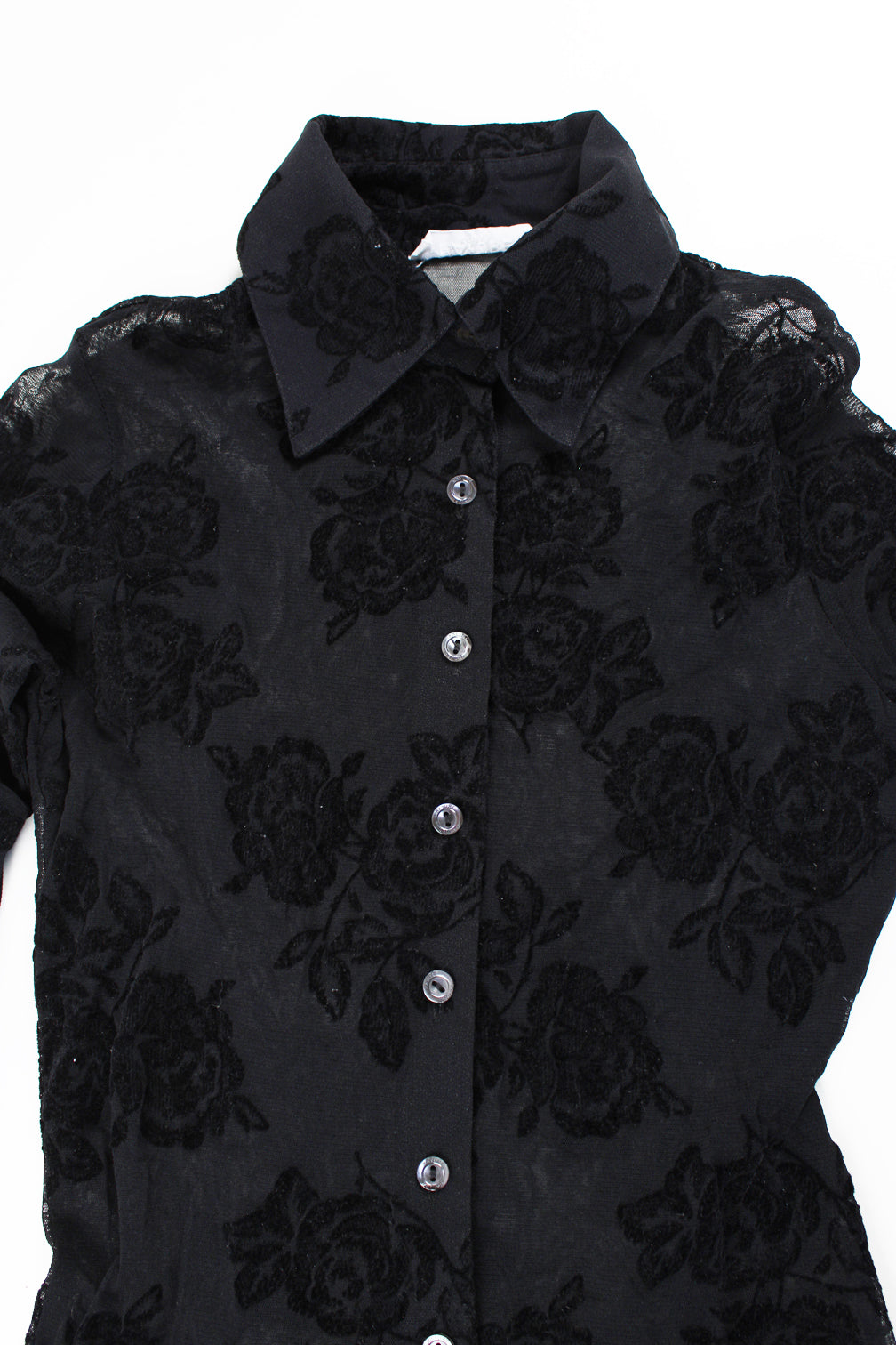 Sheer black shirt with flocked velvet rose detail. Has elasticated hem and cuffs.  good condition  Size in Label:   No Size - Measures like a size S/M (measurements taken un-stretched, made from stretchy material so could fit multiple sizes)  Our Measurements:  Chest: 17 inches  Length: 21 inches