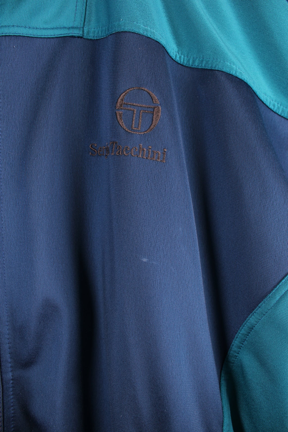 Vintage blue Sergio Tacchini tracksuit top featuring embroidered logo, blue panels and branded stripes down each arm.