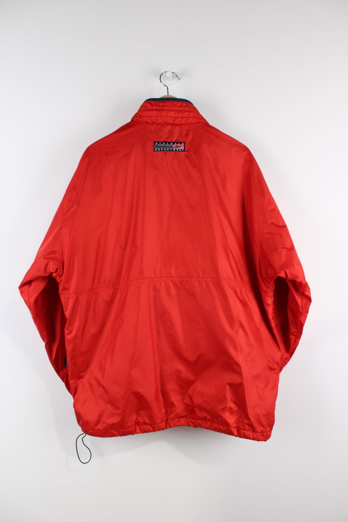 Vintage Reebok red pullover jacket with half zip, embroidered logo, packaway hood and large central pocket.