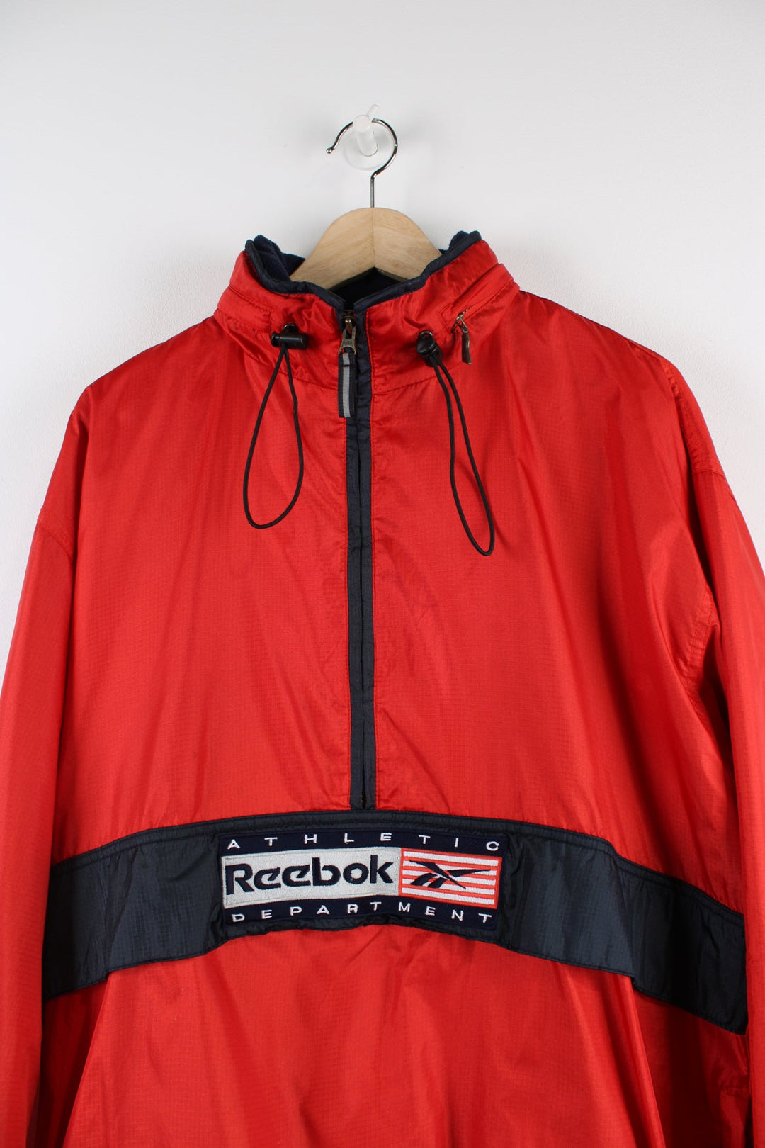 Vintage Reebok red pullover jacket with half zip, embroidered logo, packaway hood and large central pocket.