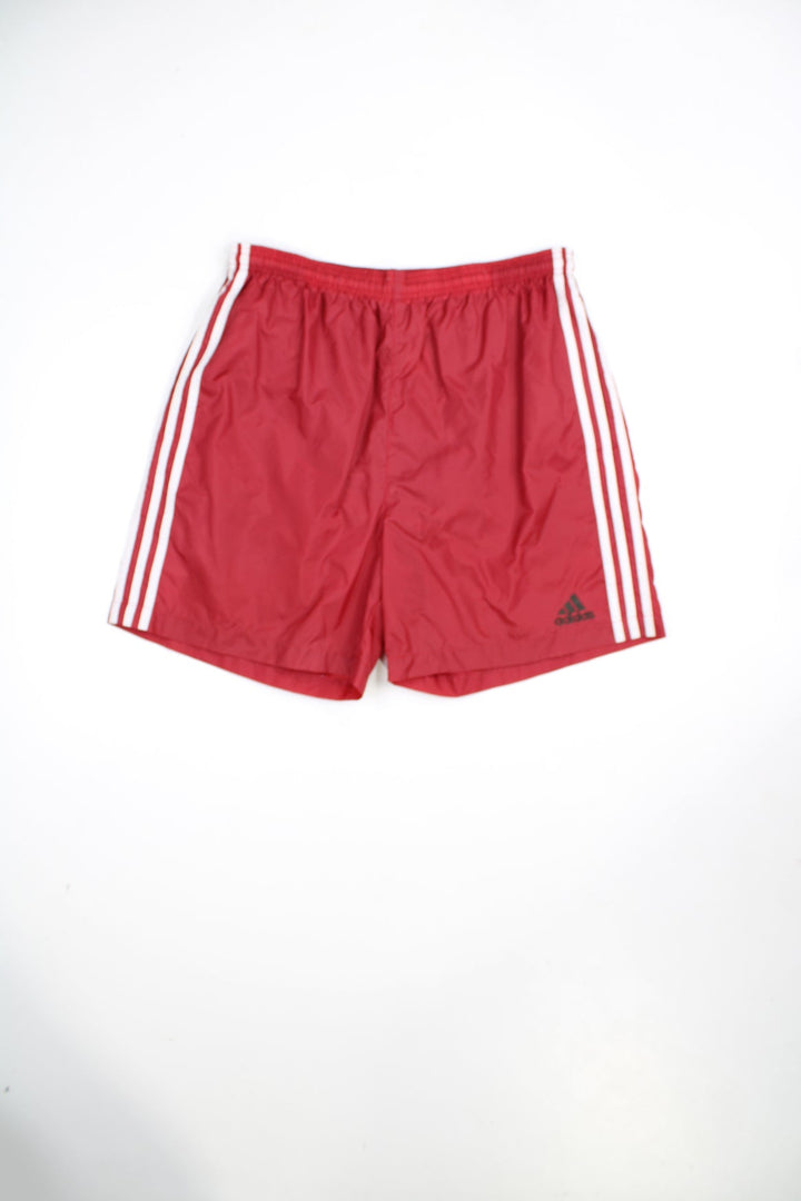 Red Adidas shorts with elasticated waistband and tie waist. Features embroidered logo and signature 3 stripes.