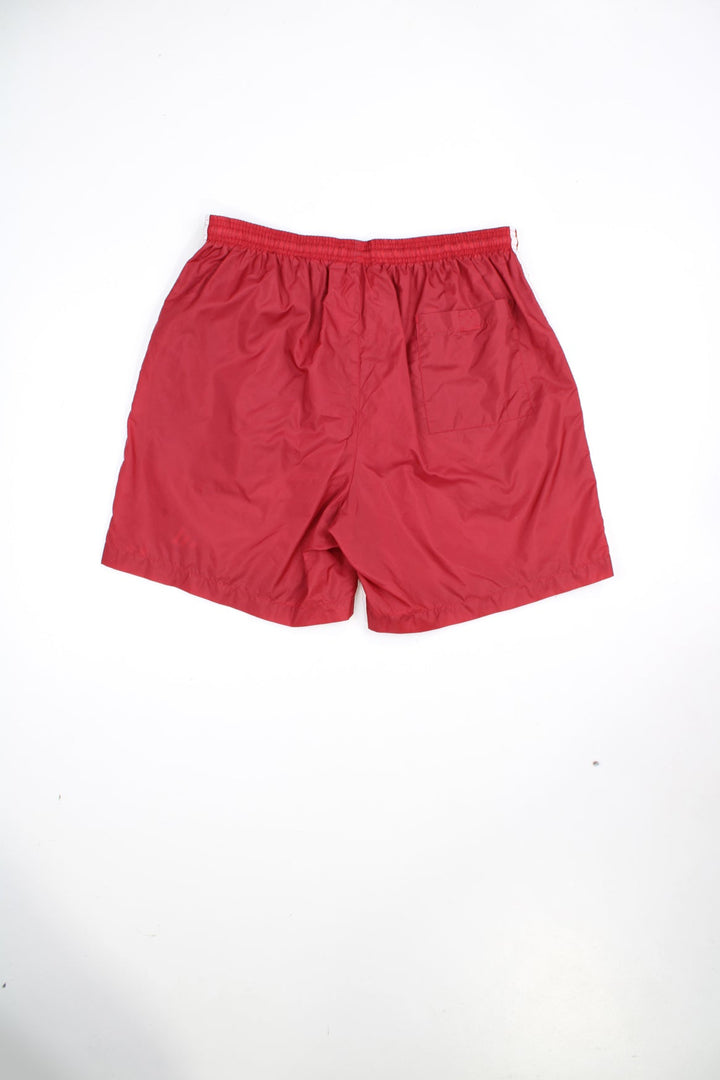 Red Adidas shorts with elasticated waistband and tie waist. Features embroidered logo and signature 3 stripes.