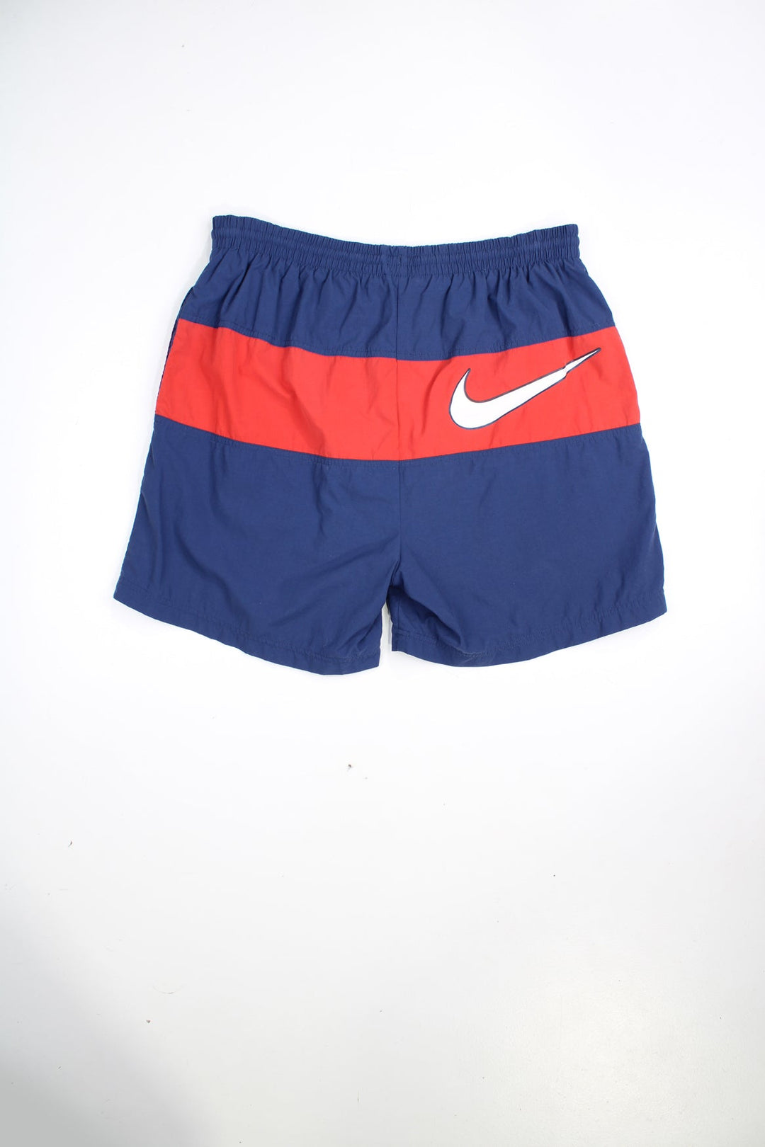 Blue and red vintage Nike swim shorts with elasticated waist and drawstring. Features embroidered logo and printed logo on the back.