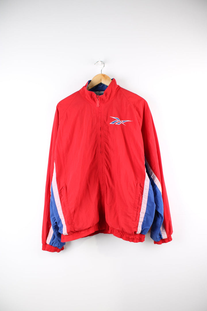 Vintage Reebok red and blue tracksuit jacket with embroidered logo on the chest and stripe panel down the sleeves.