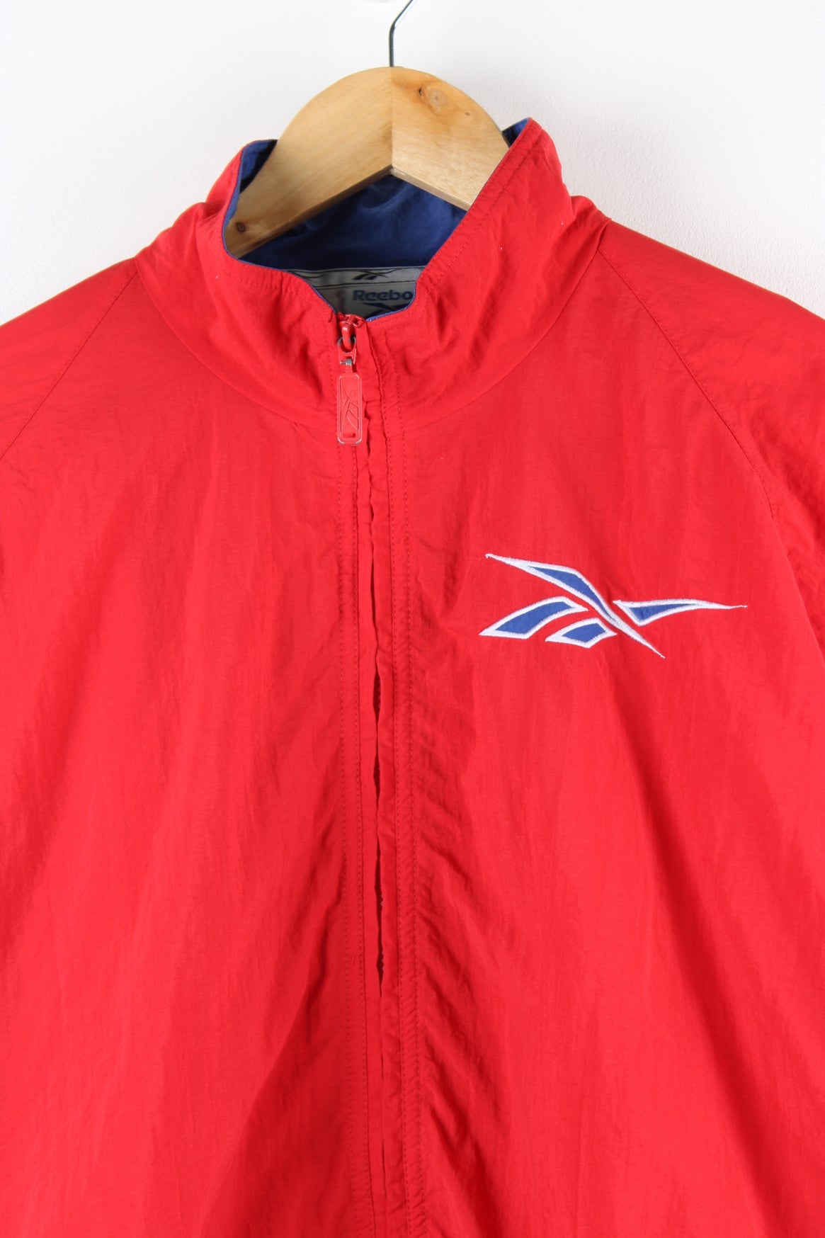 Vintage Reebok red and blue tracksuit jacket with embroidered logo on the chest and stripe panel down the sleeves.