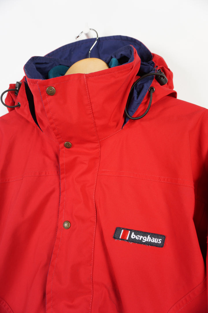 Berghaus red zip through waterproof jacket with removable fleece lining and draw string waist, embroidered logo on the chest and foldaway hood