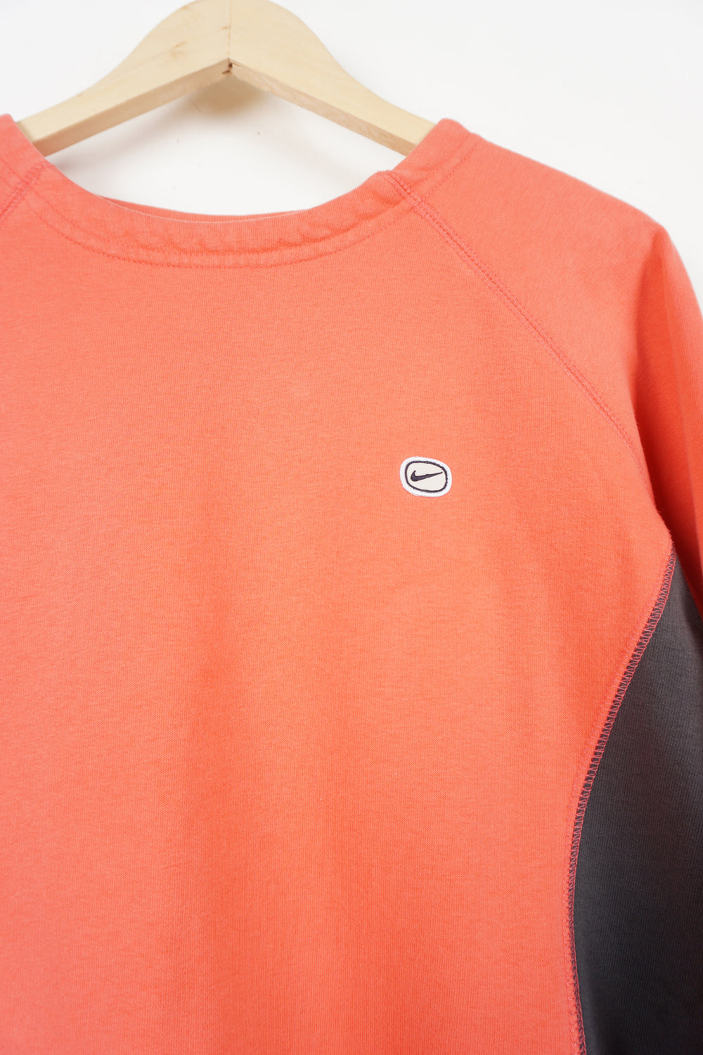 Y2K coral pink Nike crewneck sweatshirt with embroidered logo on chest and grey side panels. Also has elastic drawstring around the hem.