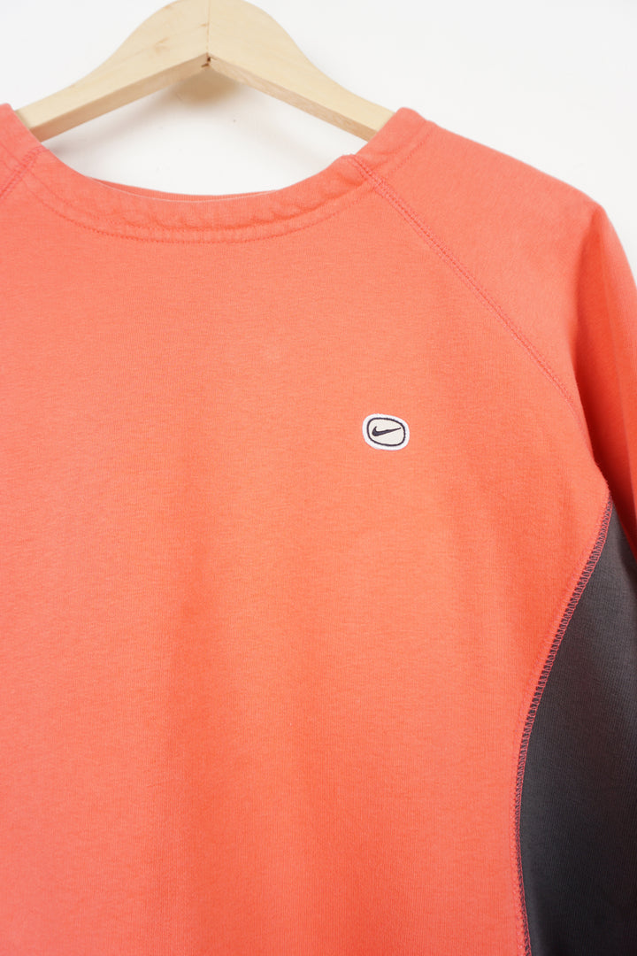 Y2K coral pink Nike crewneck sweatshirt with embroidered logo on chest and grey side panels. Also has elastic drawstring around the hem.