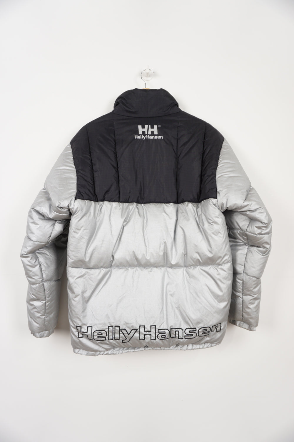 Silver and black Helly Hansen puffer jacket with multiple pockets, drawstring hem and embroidered spell-out logos on front and back