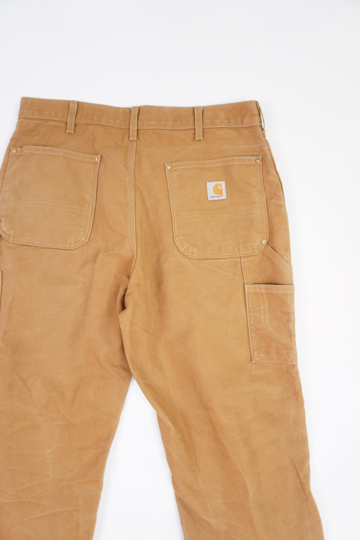 Tan Carhartt heavy duty cotton carpenter jeans with multiple pockets and double knee