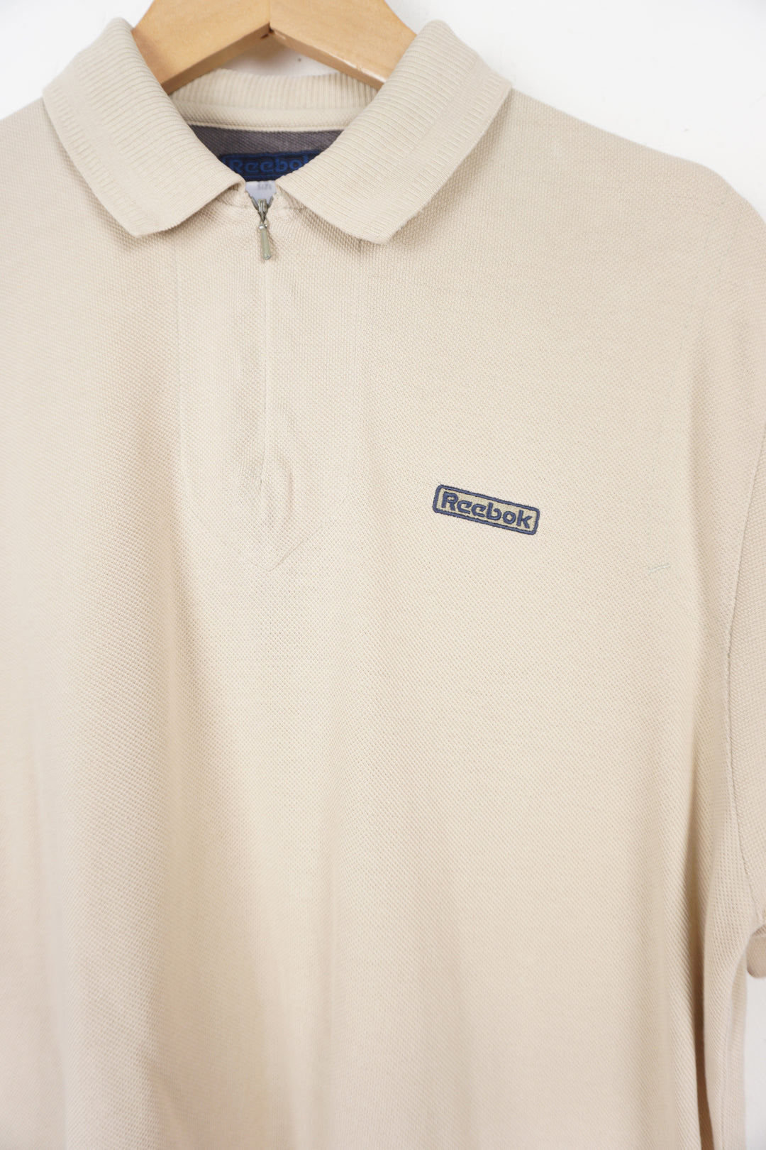 Reebok beige polo shirt with embroidered logo on the chest and 1/4 zip detail