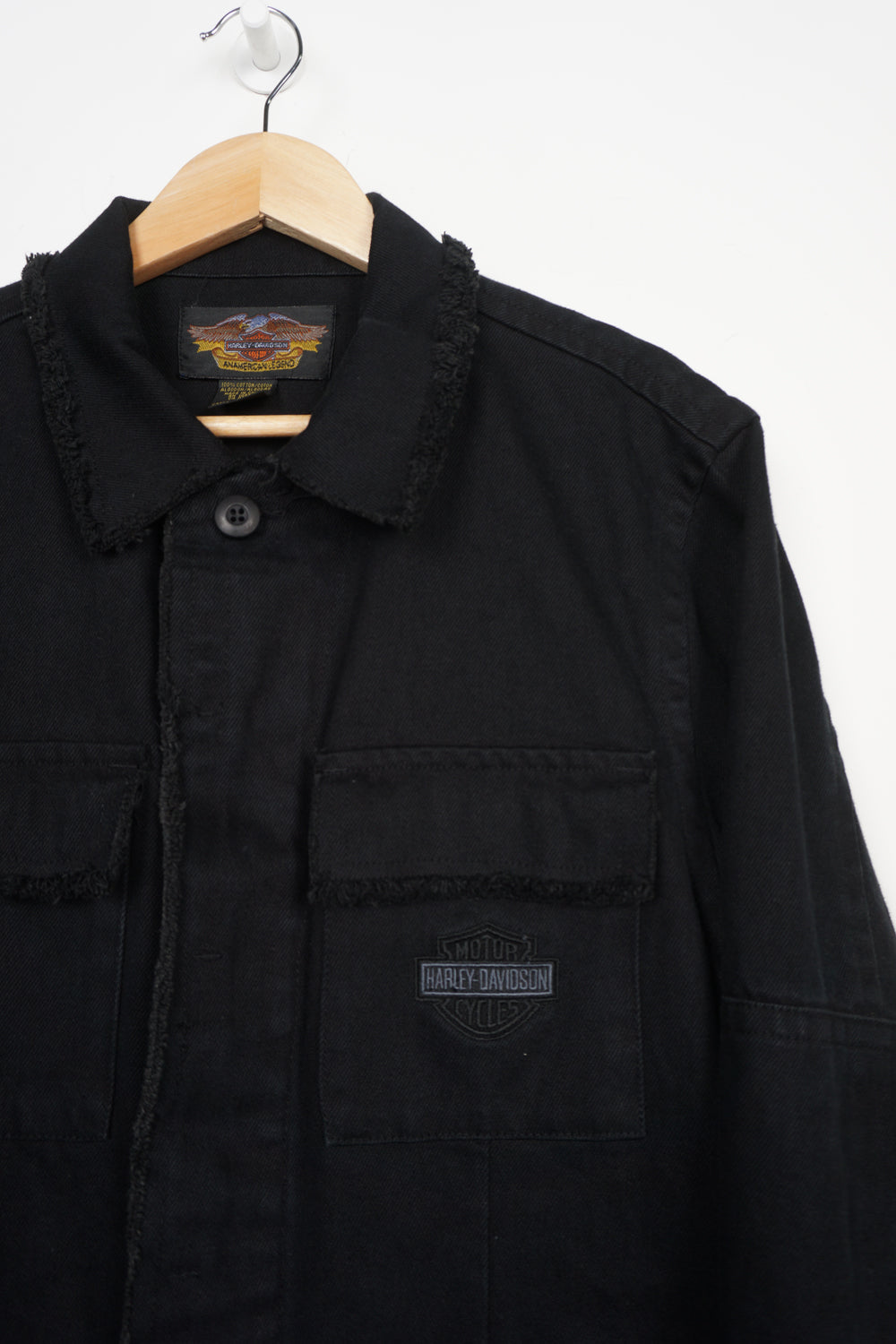 All black Harley Davidson denim jacket with embroidered logo on the front pocket and frayed edge details