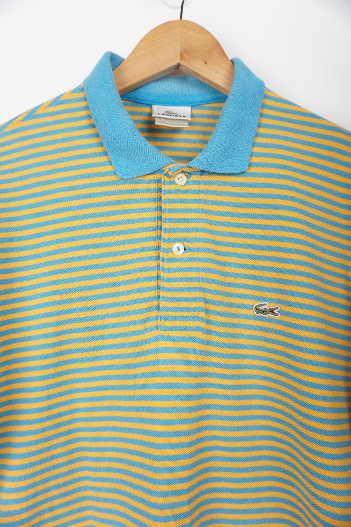 Vintage Lacoste blue and yellow striped polo shirt with embroidered logo. good condition- small hole under one armpit Size in Label: S Our Measurements: Chest: 20 inchesLength:&nbsp; 28 inches Please ensure you check all measurements. ** All our items are pre-loved and as a result may show signs of wear due to the age of the product, for any questions about this or any other item please email hello@vintage-folk.com **