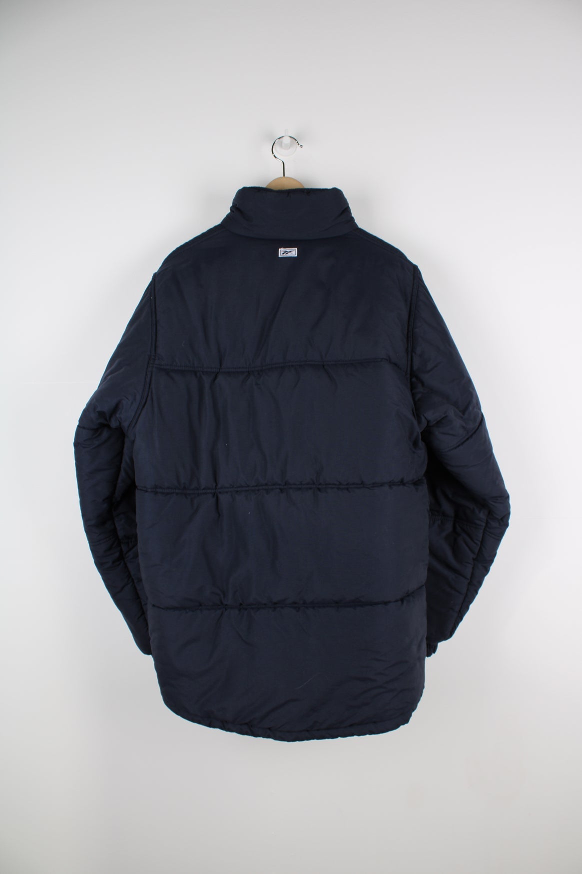 Blue Reebok puffer coat with embroidered logo on the chest.