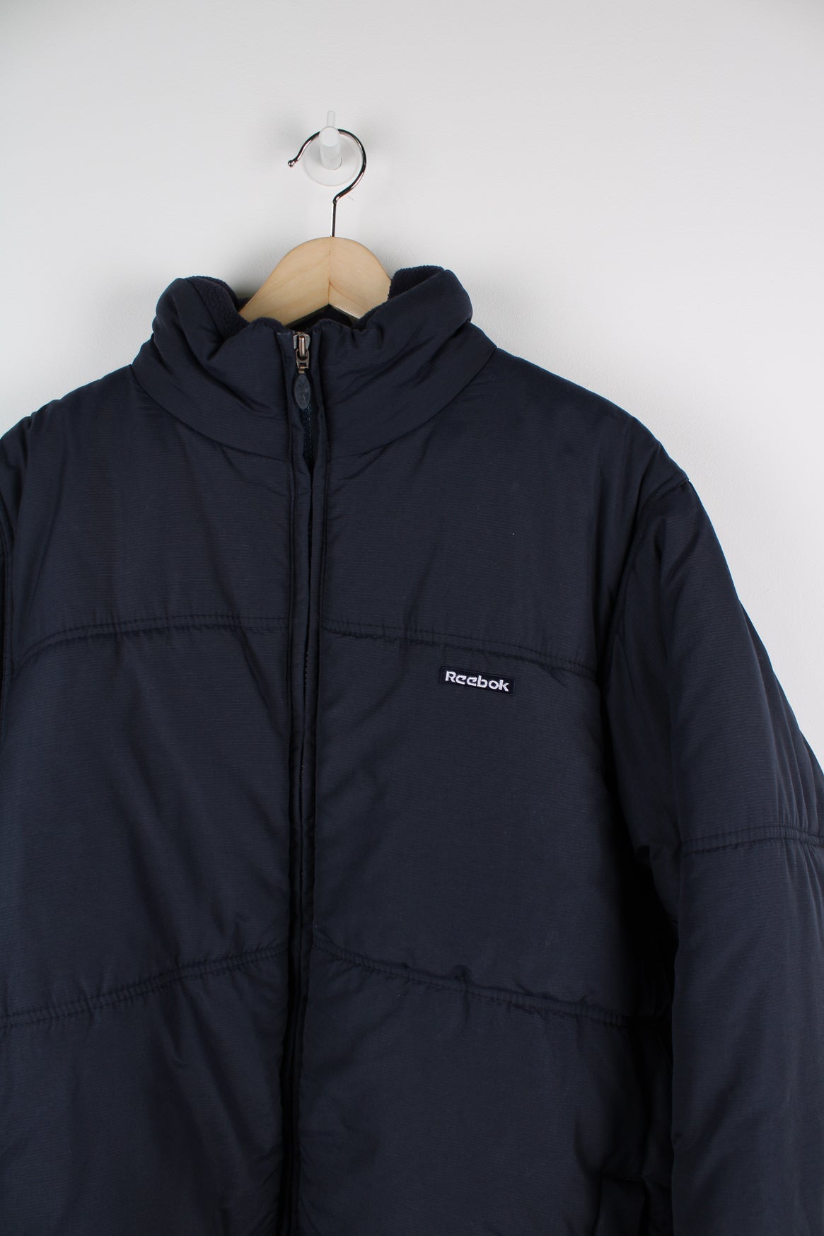 Blue Reebok puffer coat with embroidered logo on the chest.