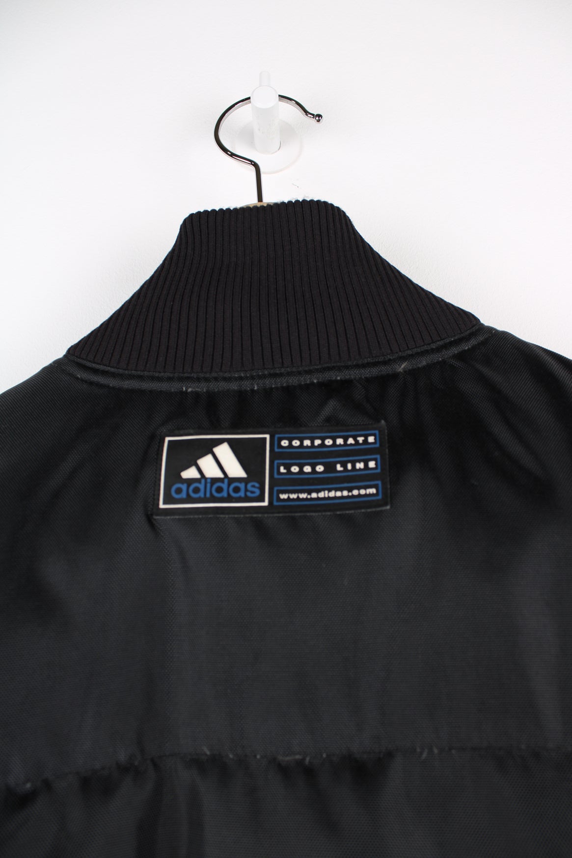 Black Adidas puffer coat with embroidered logo on the chest.