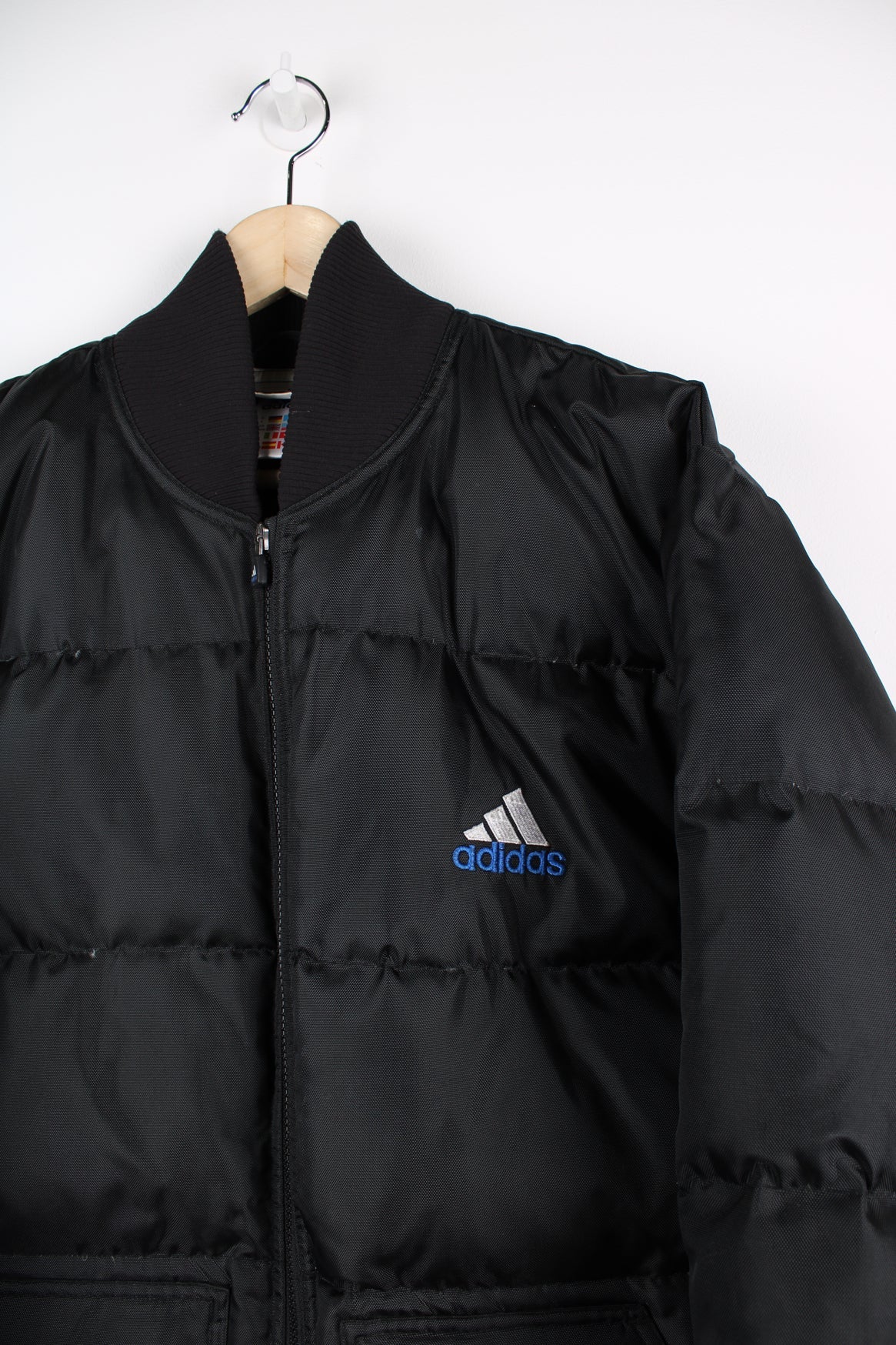 Black Adidas puffer coat with embroidered logo on the chest.