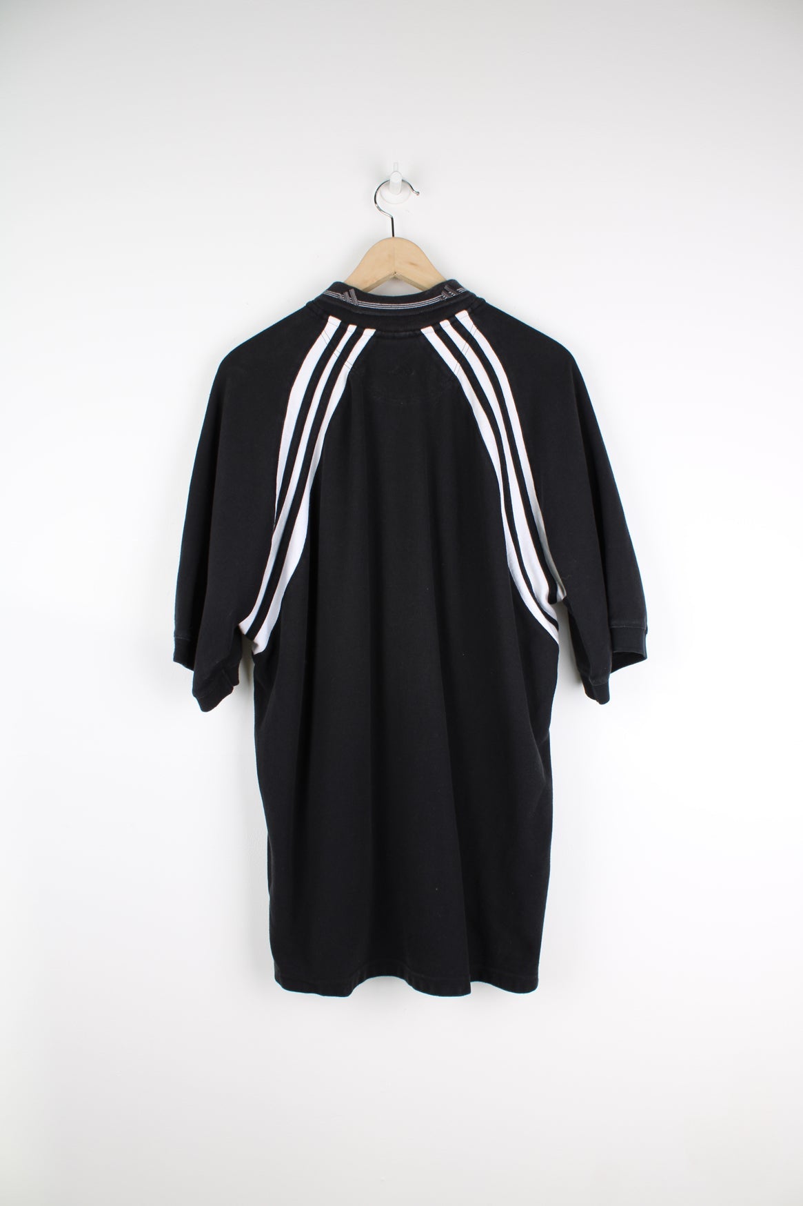 Black Adidas polo shirt with embroidered logo on the chest and stripe feature down each arm.