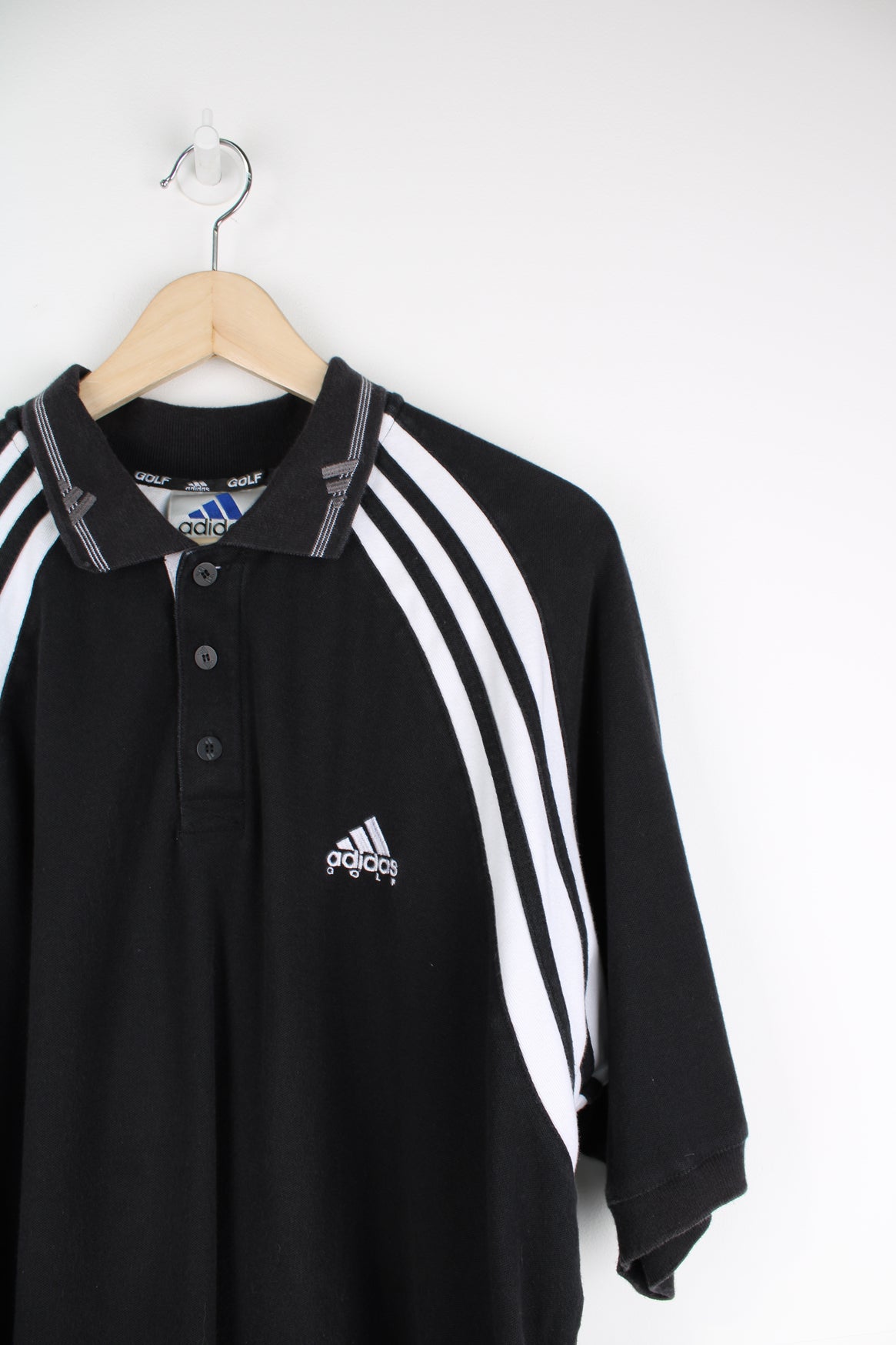 Black Adidas polo shirt with embroidered logo on the chest and stripe feature down each arm.