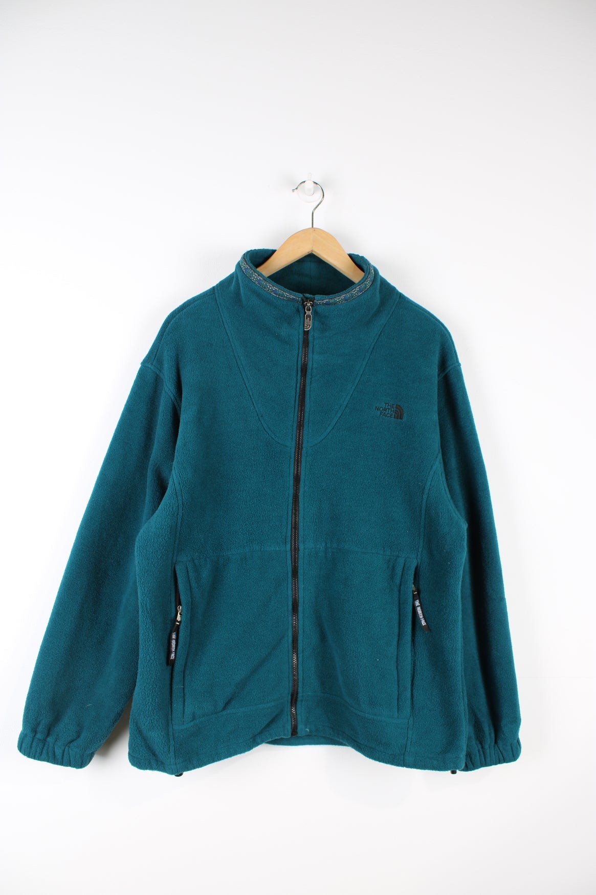 The North Face green zip through fleece. Features embroidered logo on the chest and aztec print detailing on the neck.