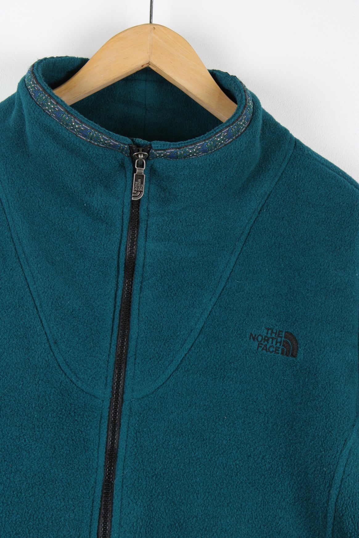 The North Face green zip through fleece. Features embroidered logo on the chest and aztec print detailing on the neck.